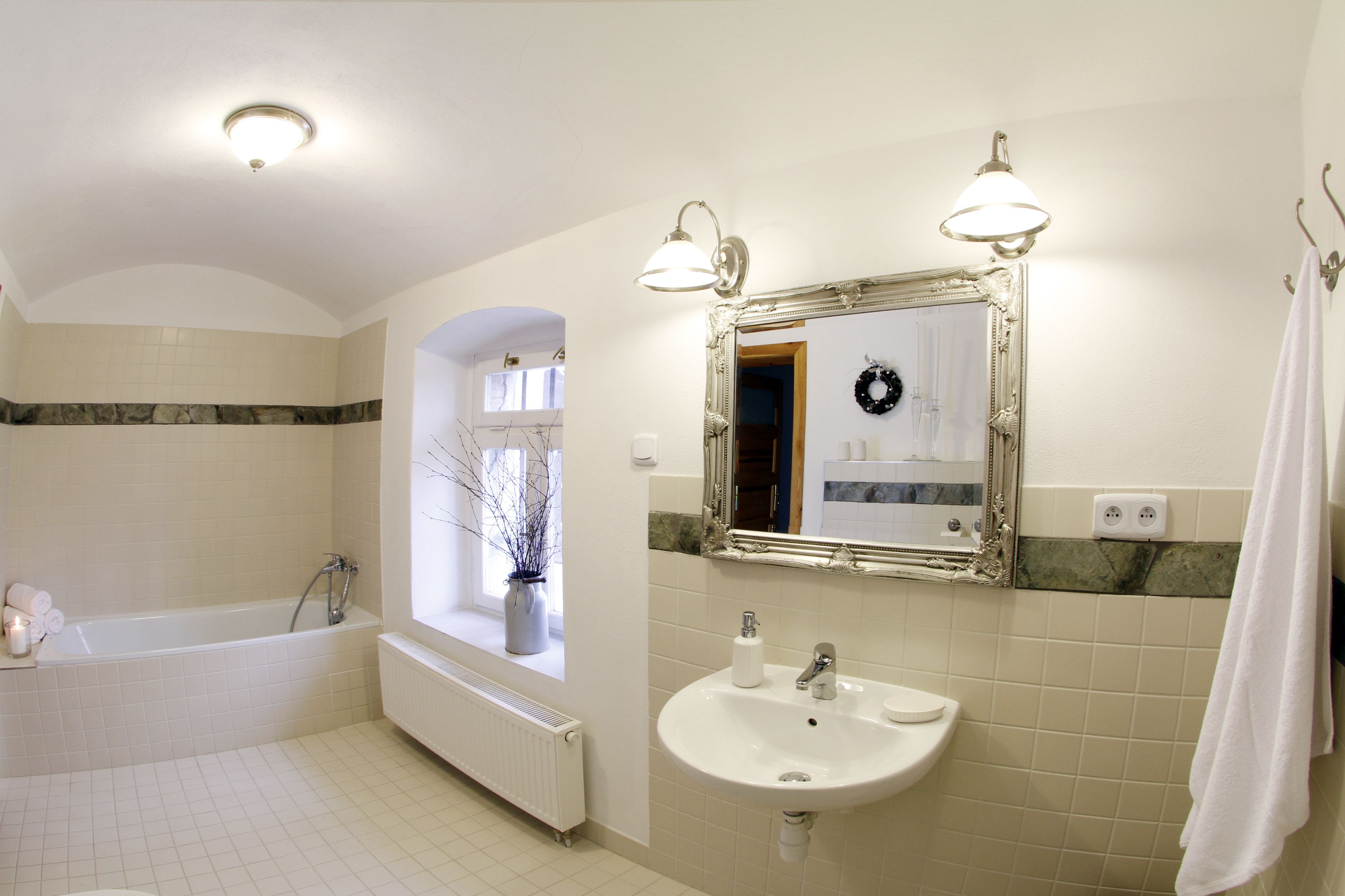 A bathroom with a bathtub, sink, and mirror.