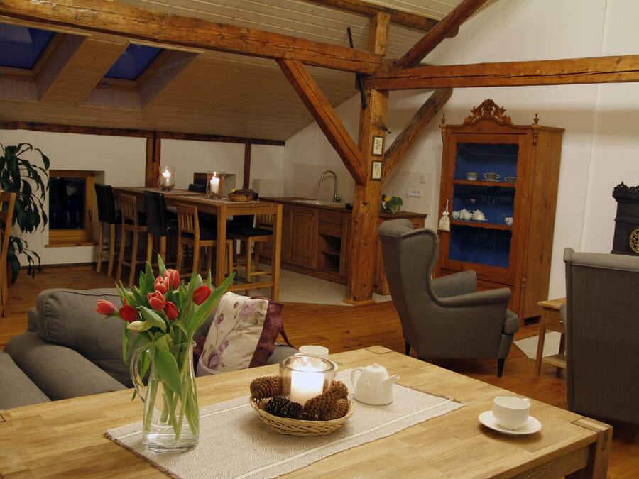 A cozy living room with a wooden table, a vase of tulips, a lit candle, and a rustic wooden cabinet.