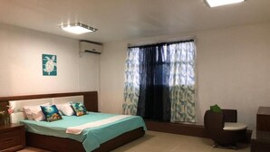 Un dormitorio con cama, ventana con cortinas, una silla y una mesita.