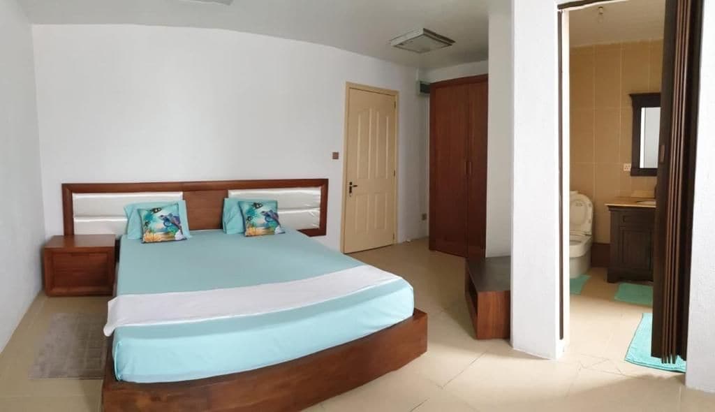 Ein Schlafzimmer mit einem Bett, Nachttischen, einem hölzernen Kopfteil und einer Tür zu einem Badezimmer.