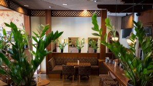 A restaurant interior with wooden furniture, potted plants, and a chalkboard menu. - Comfort Guesthouse (Jakobstad)
