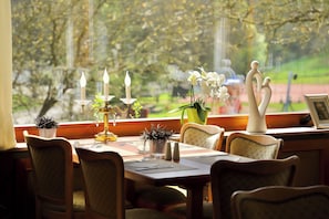 Un comedor con una mesa dispuesta para dos personas, que incluye un candelabro, un florero con flores y una figura decorativa.