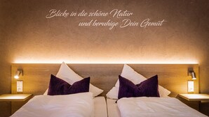 A hotel room with two beds, a wooden headboard, and a wall-mounted light fixture.