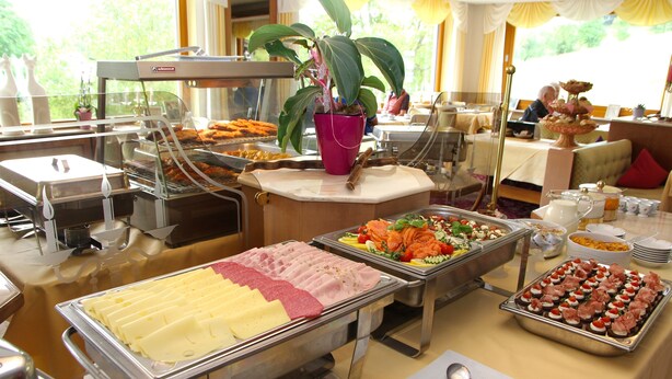 A buffet with various food options, including meats, cheeses, and salads.