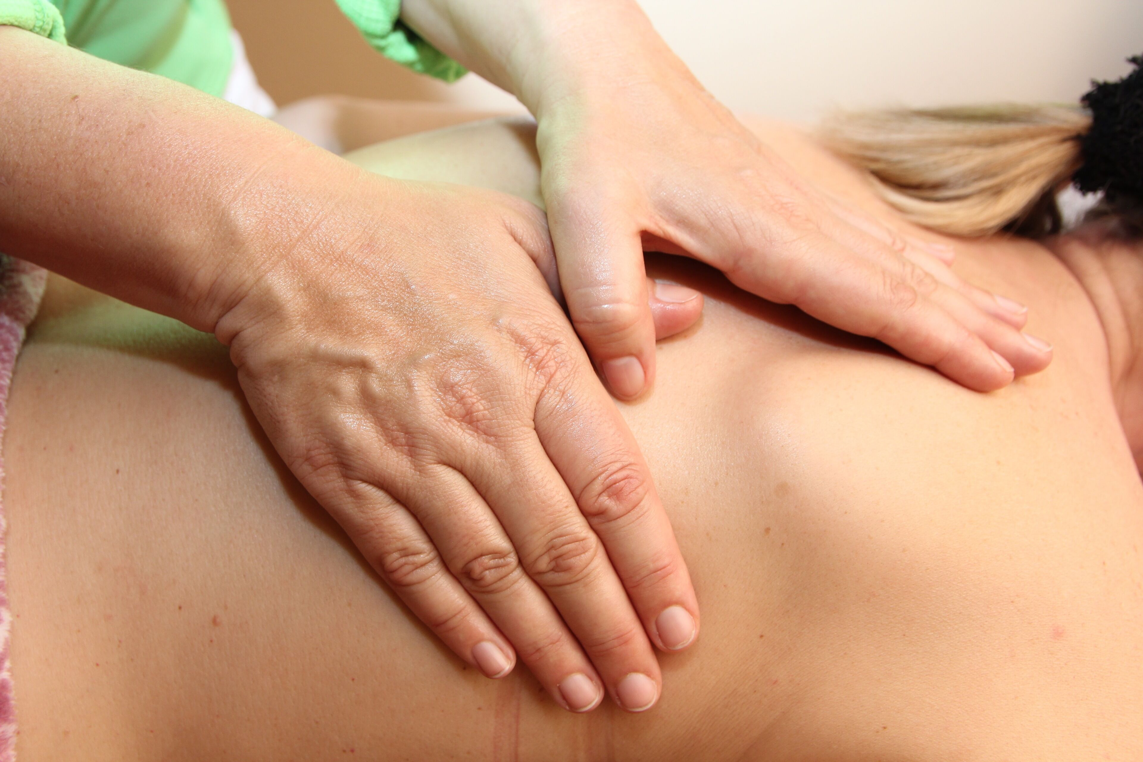Nahaufnahme von Händen, die eine Rückenmassage geben.