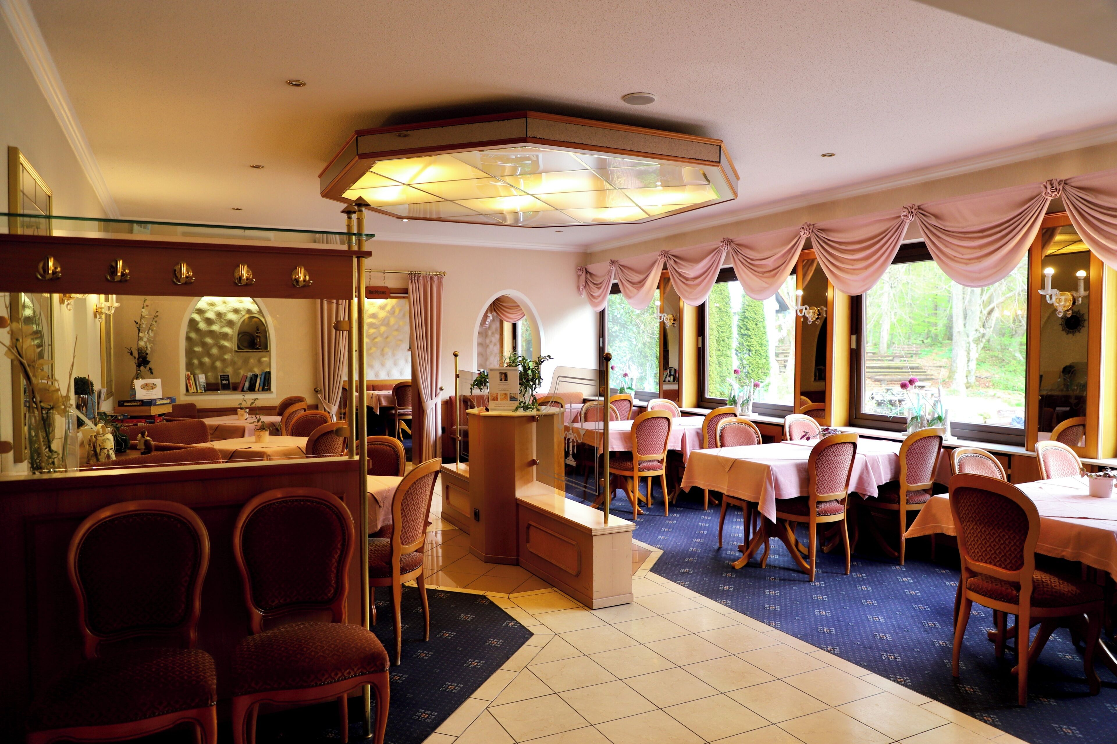 A restaurant with a bar area, multiple dining tables, and chairs.