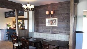 Un restaurant aux murs en bois, doté d’un bar et d’un espace où sont disposées des tables et des chaises.