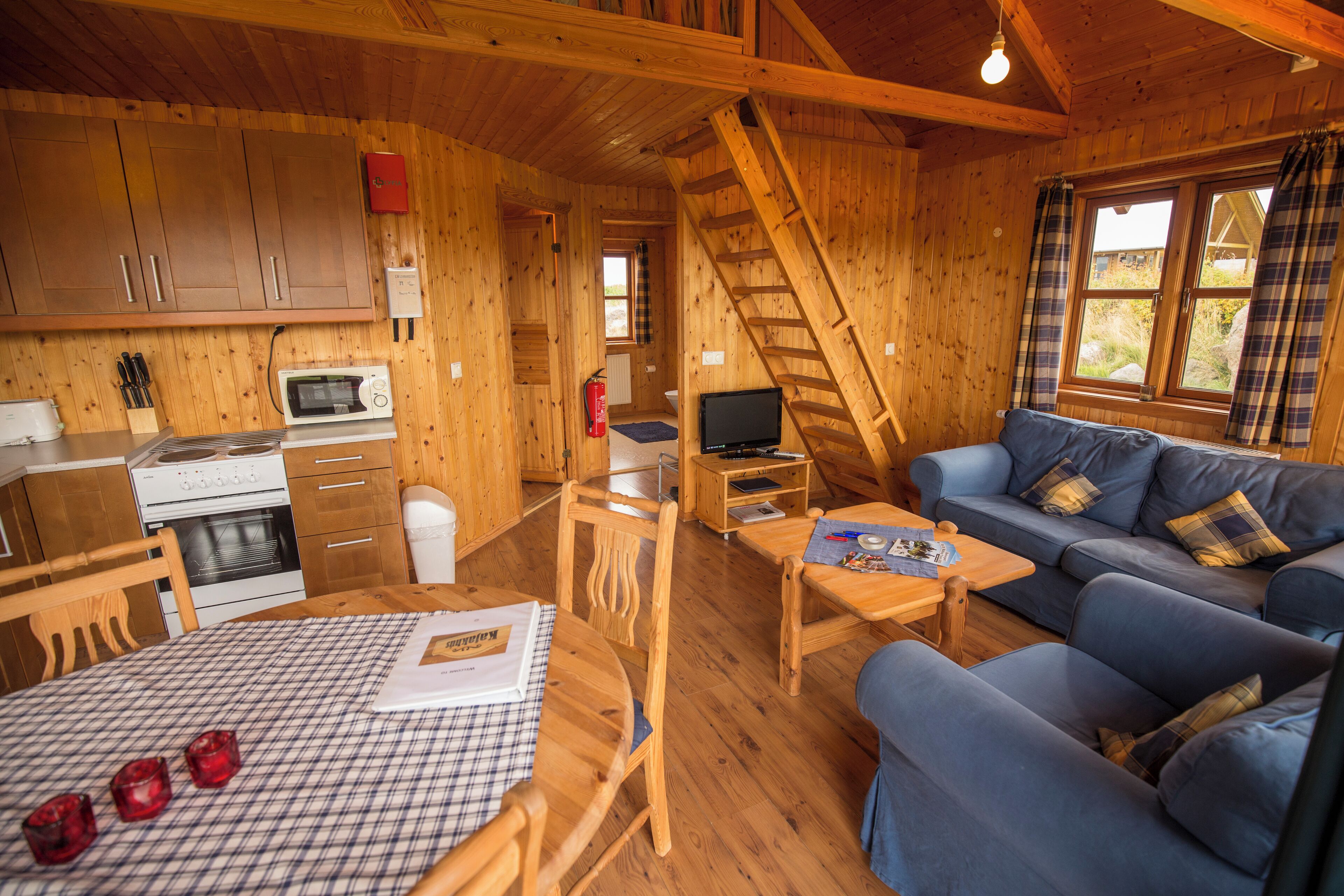 A wooden cabin interior with a kitchen, dining area, and living room.