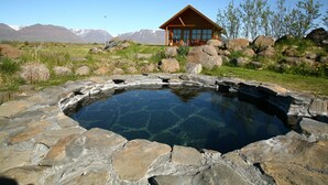 Une cabane en bois avec une piscine en pierre, entourée de rochers.