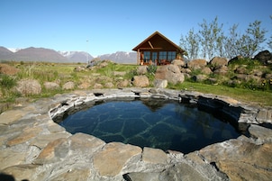 A wooden cabin with a stone swimming pool surrounded by rocks.