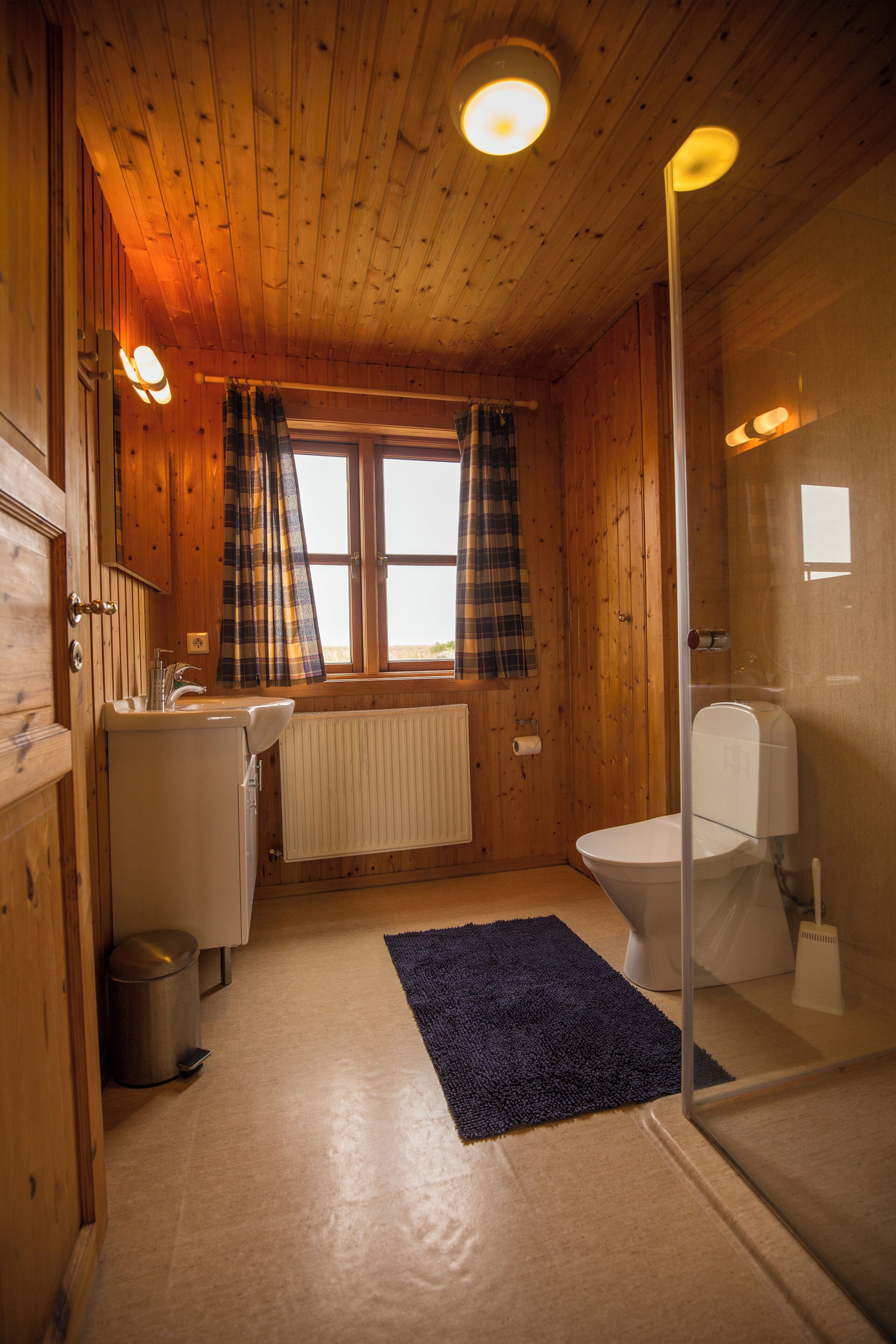 Een houten badkamer met toilet, wastafel en raam.