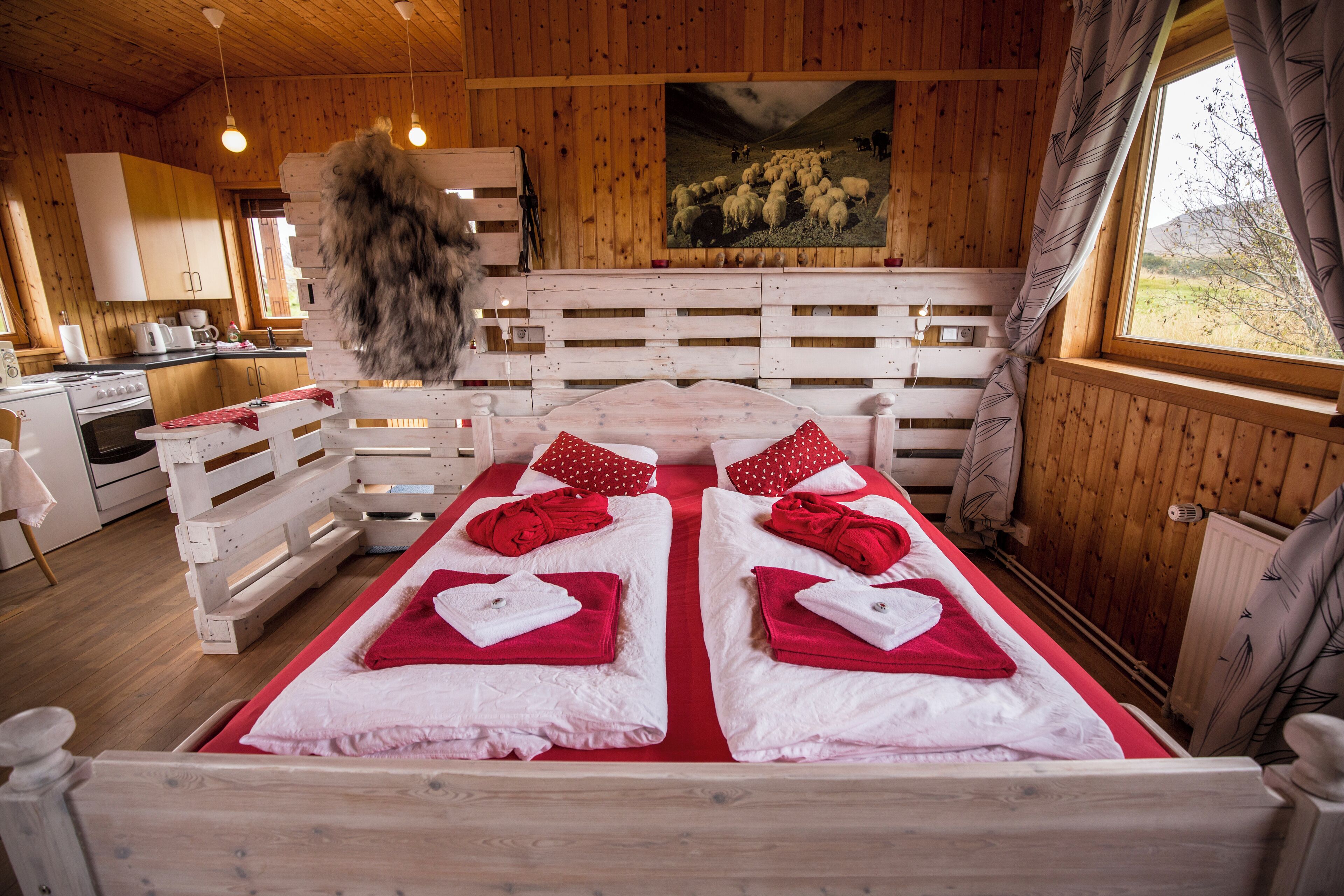 Una cabaña de madera con una cama, una cocina y un ventanal grande.