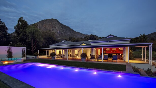 A modern house with a swimming pool, outdoor seating, and a mountain backdrop. - La Providence Guest House & Wine Farm (Franschhoek)
