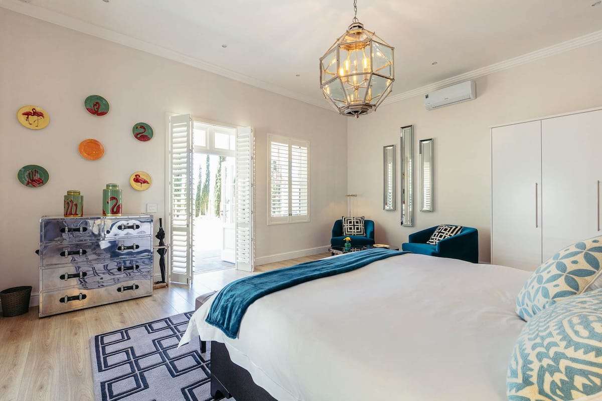 A bedroom with a large bed, a chandelier, a dresser, and a mirror.