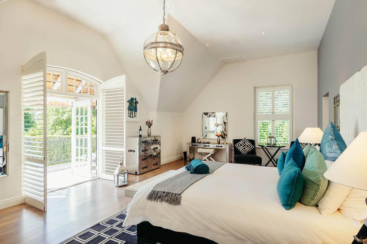 A bedroom with a large bed, a desk, and a view of the outdoors.