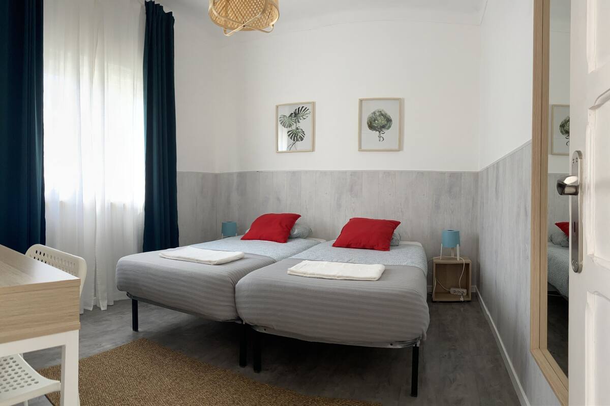 Een slaapkamer met twee bedden, een houten bureau en een spiegel.