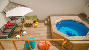 A wooden deck with a hot tub, seating area, and a table with chairs. - Surfer's Den Ericeira (Mafra)