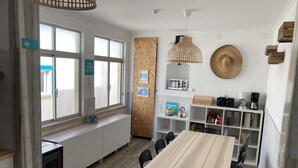 A modern kitchen with a wooden table and chairs, a built-in oven, and a coffee station. - Surfer's Den Ericeira (Mafra)