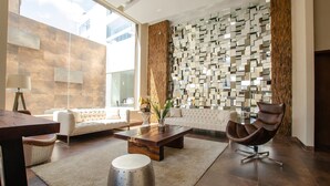 A modern living room with a sofa, a wooden coffee table, a brown leather chair, and a decorative wall.