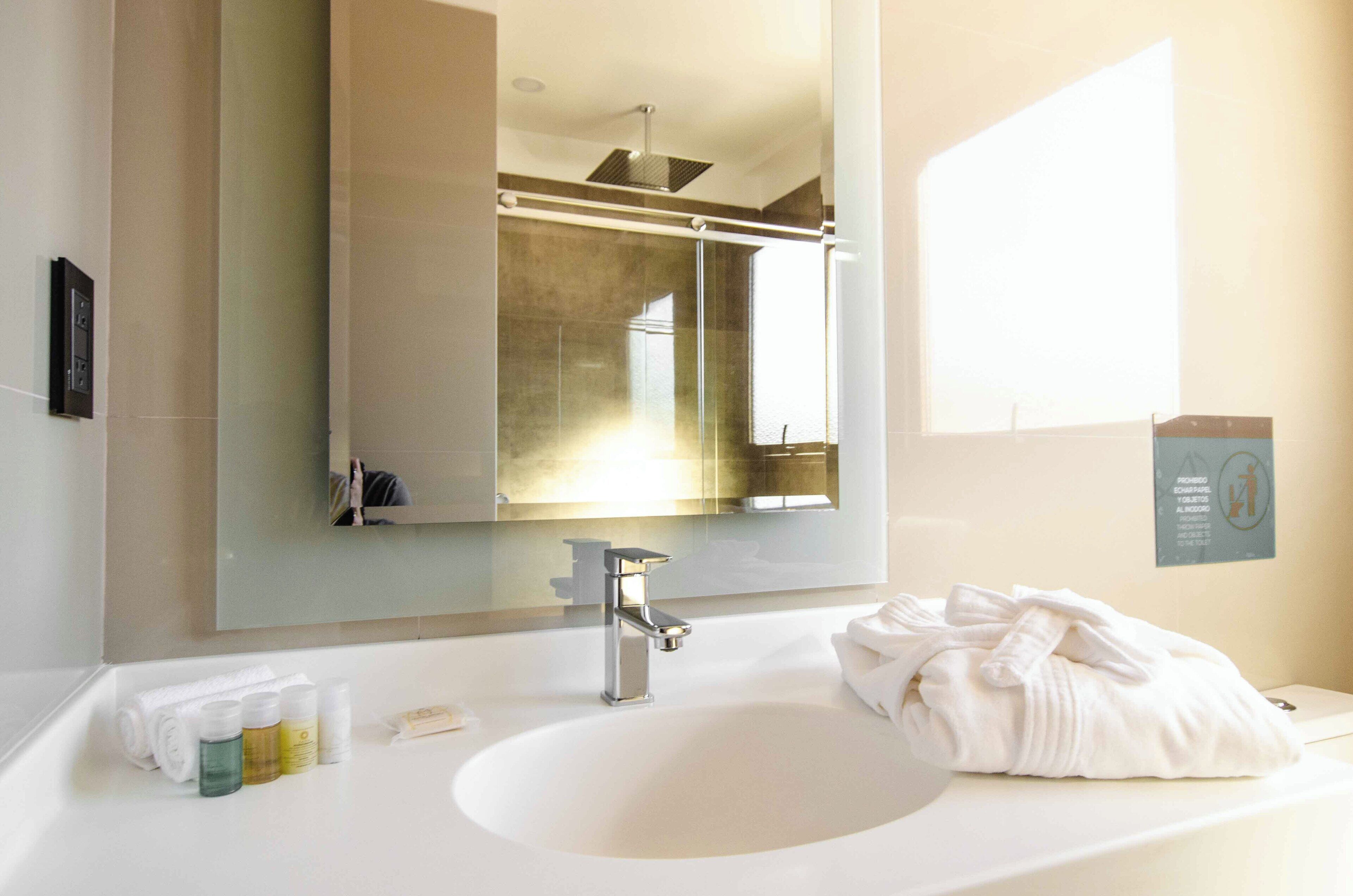 Un baño moderno con un espejo grande, un lavabo blanco y una toalla sobre la encimera.