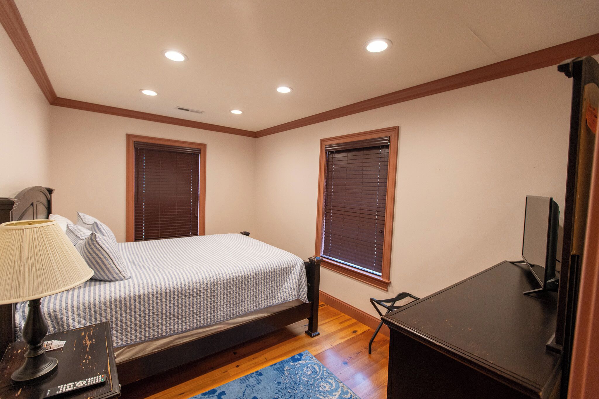A bedroom with a bed, a desk, a lamp, and a television.