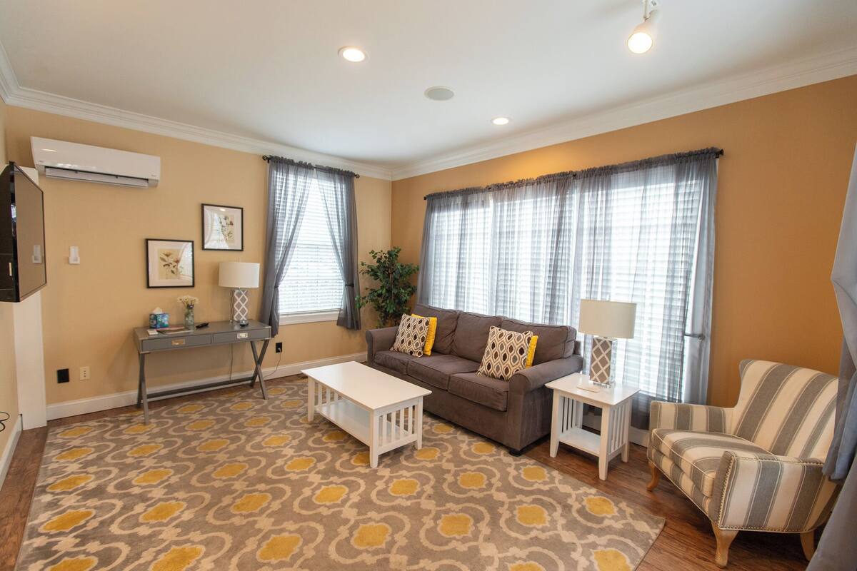 A living room with a sofa, armchair, coffee table, side table, and a patterned rug.