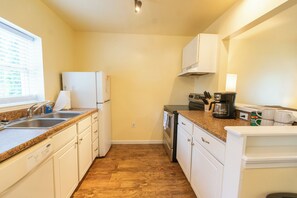 A compact kitchen with white cabinets, a granite countertop, a built-in oven, and a coffee maker.