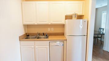 A compact kitchen with white cabinetry, a dishwasher, and a refrigerator.