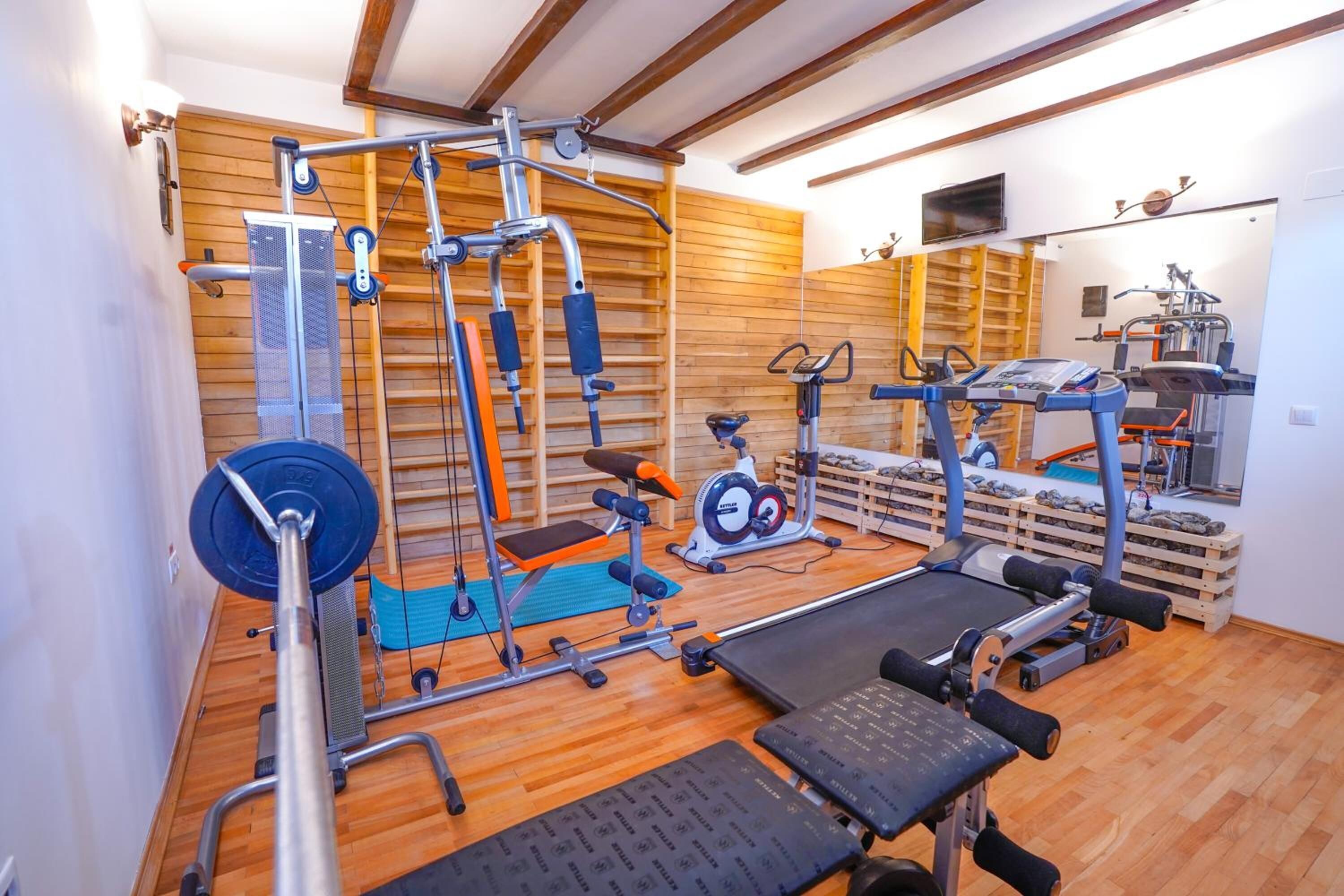 Ein Heimfitnessraum mit verschiedenen Trainingsgeräten, darunter eine Langhantelbank, eine Kurzhantelbank und eine Klimmzugstange.
