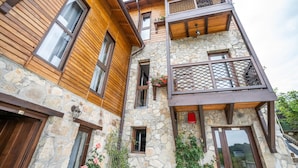 A multi-story building with wooden and stone facades, balconies with mesh railings, and windows with wooden shutters. - Felix Pension (Prajila)