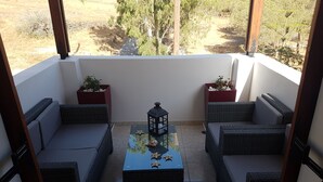 A balcony with wicker furniture, two potted plants, and a lantern. - Santorini Family Apartments (Santorini)