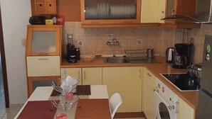 A compact kitchen with a dining area, featuring a built-in oven, a sink, and a coffee maker. - Santorini Family Apartments (Santorini)