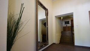 Ein Flur mit einem großen, verzierten Spiegel, einer Treppe und einer Zimmerpflanze.