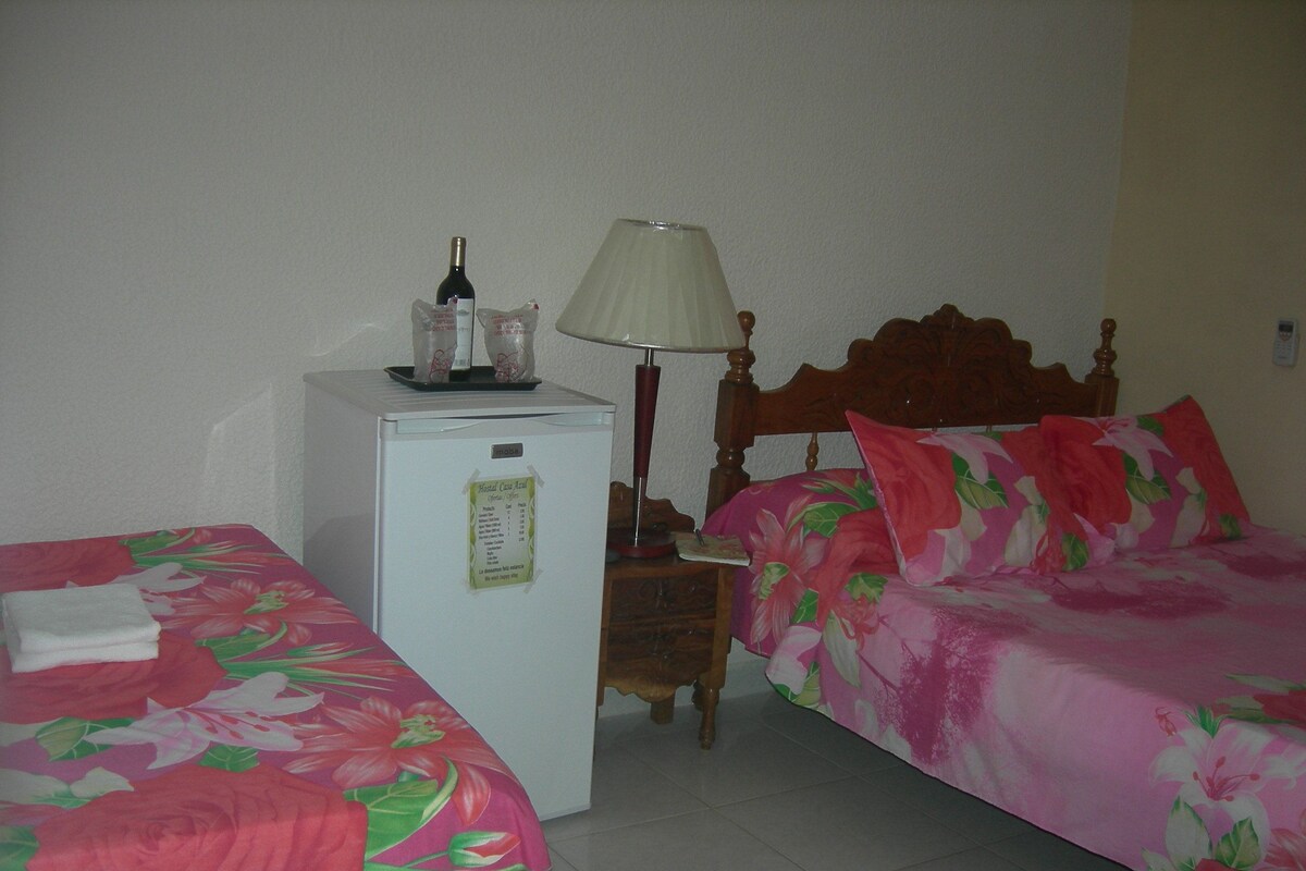 Ein Hotelzimmer mit zwei Betten, einem kleinen Kühlschrank, einem Nachttisch und einer Lampe.