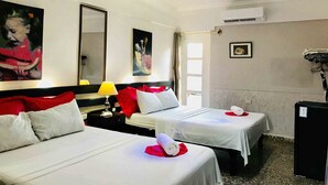 A hotel room with two beds, a nightstand, a lamp, a mirror, and a refrigerator. - Casa Las Artes (Trinidad)