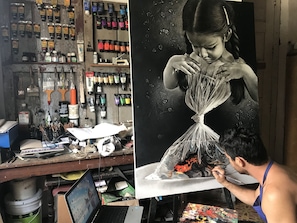 A workspace with art supplies, a laptop, and a painting in progress. - Casa Las Artes (Trinidad)