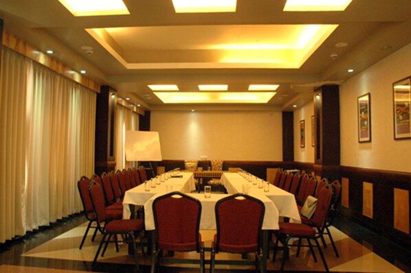 A conference room with a long table, red chairs, and a white tablecloth. - Hotel Mirabel (Korai)