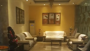 A spacious living room with a white sofa set, a coffee table, and a chandelier.