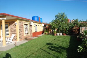 A residential property with a well-maintained lawn, a brick house with a red roof, and a blue water tank. - Casa Micher y Deylin (Viñales)