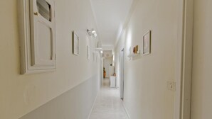 Un pasillo largo y estrecho con paredes blancas y piso de baldosas.