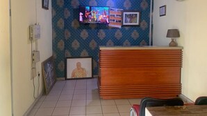 A room with a wooden ceiling, a TV mounted on the wall, a reception desk, and a framed picture on the wall. - Mikaddo City Inn (Kumasi)