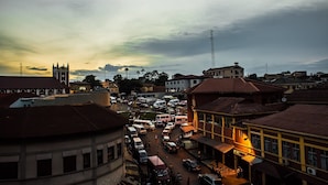 A busy urban street with buildings, vehicles, and a prominent tower. - Mikaddo City Inn (Kumasi)