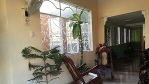 A room with a large window, a potted plant, a rocking chair, and a wooden chair. - Hostal Juan Fernandez (Trinidad)