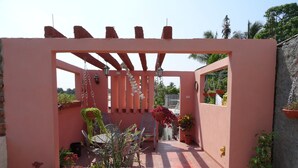 A covered patio area with a pergola, potted plants, and outdoor furniture. - Hostal Restaurante La Rosa (Trinidad)