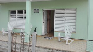 A building with a green facade, white shutters on the windows, and a sign indicating it is Villa Isabel y Luisito. - Villa Isabel y Luisito (Viñales)