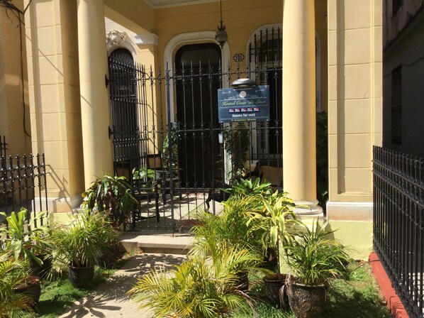 Classic hotel entrance with a welcoming wrought iron gate and steps leading to the door.