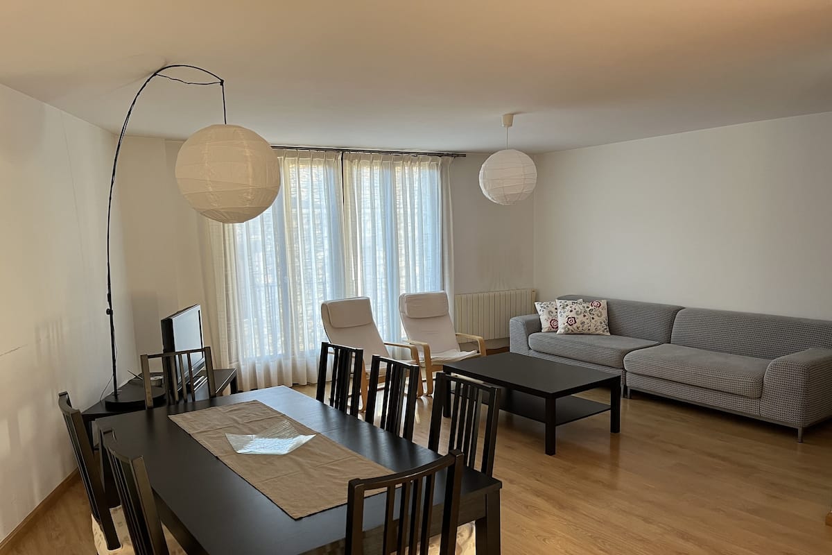 Een moderne woonkamer met een eettafel, stoelen, een bank en een salontafel.