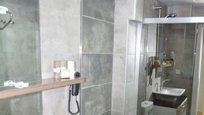 Une salle de bain moderne avec un grand miroir, un lavabo, des toilettes et un espace douche.