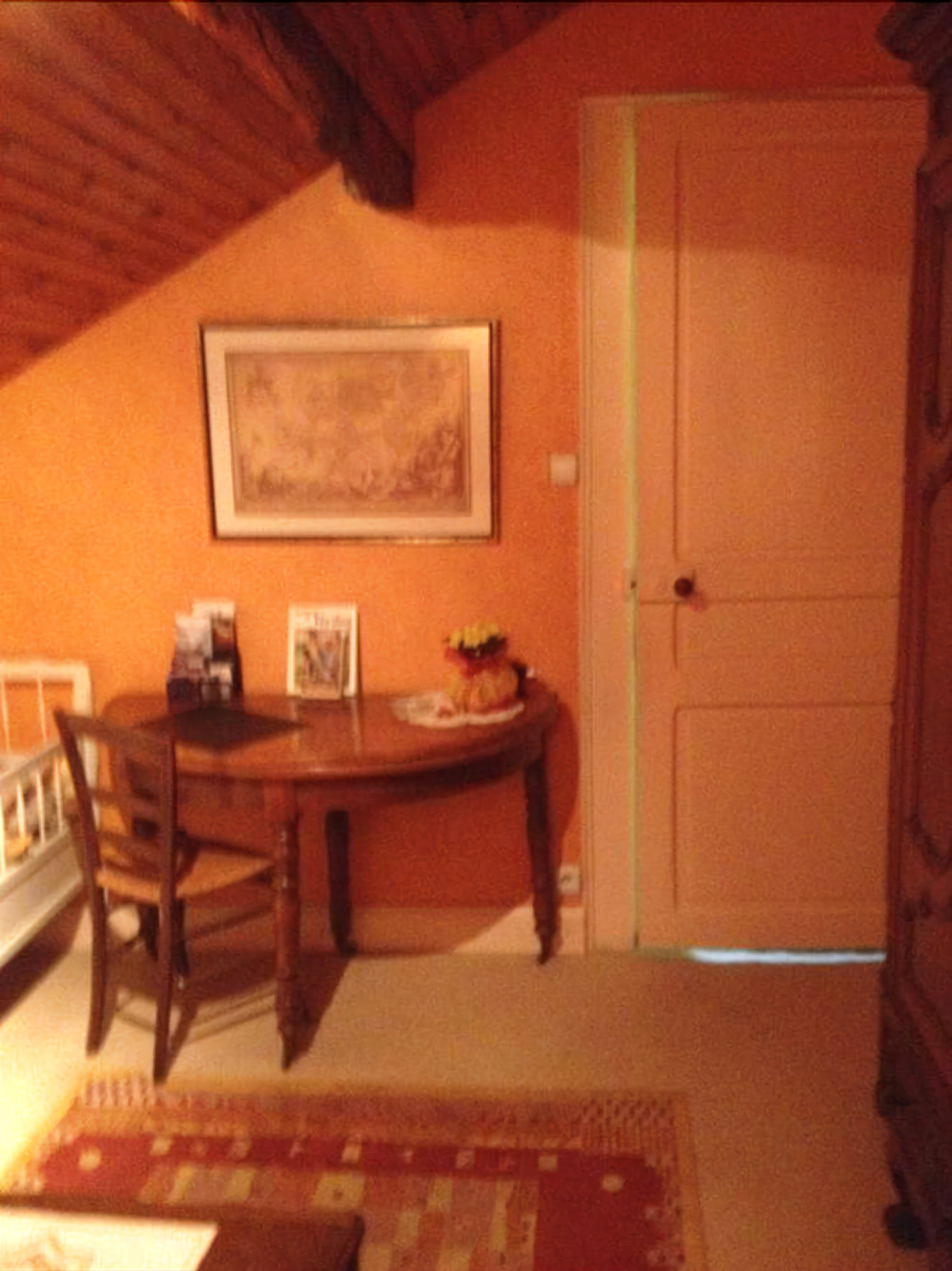 Un comedor con una mesa de madera, sillas, un cuadro en la pared y una puerta.