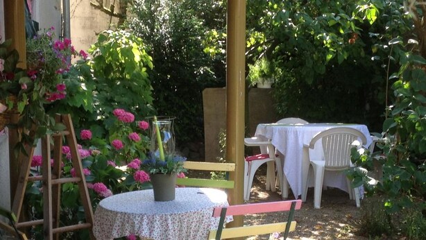 Un patio jardín con una mesa redonda, sillas y una escalera.